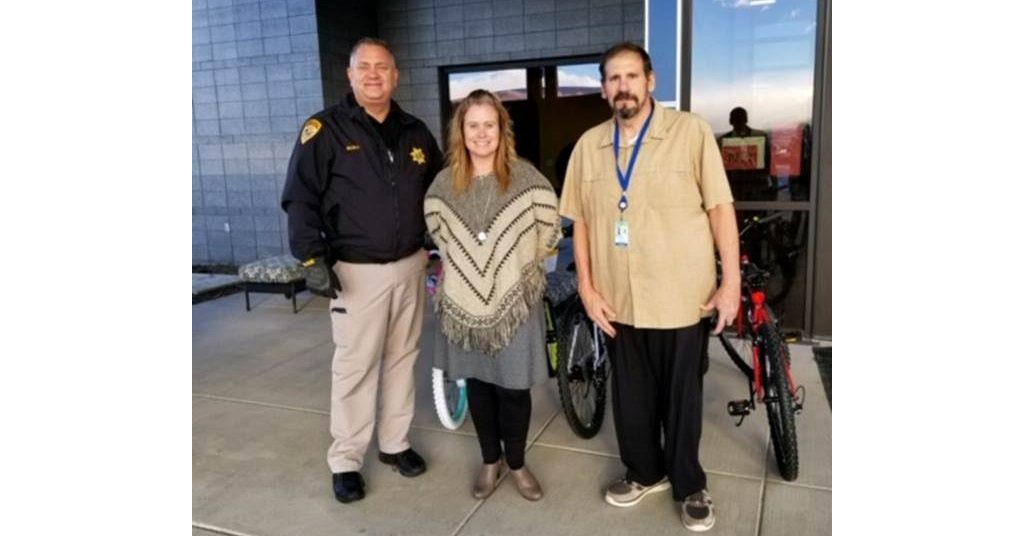 Sheriff standing with Nicole and Dirk in front of the bikes. Smiling at the camera.